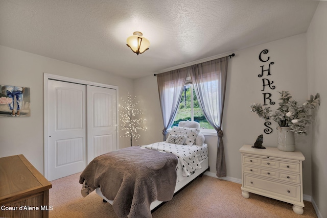 bedroom featuring a textured ceiling, baseboards, a closet, and light colored carpet