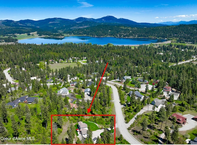 birds eye view of property featuring a wooded view and a water and mountain view