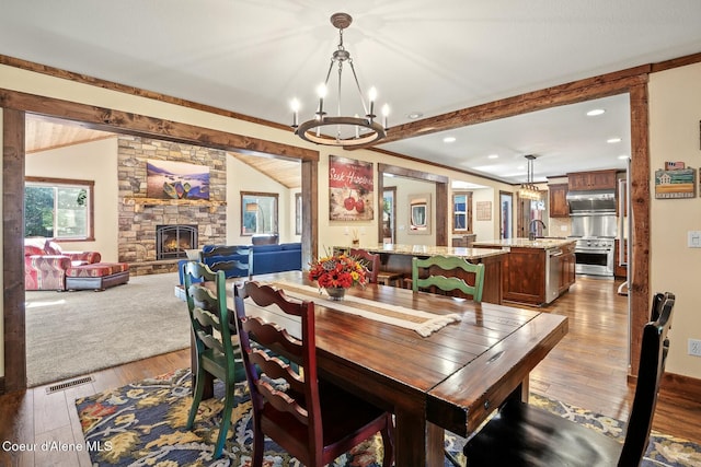 dining room with vaulted ceiling with beams, a notable chandelier, visible vents, and hardwood / wood-style floors