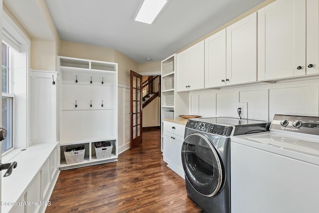 clothes washing area featuring dark wood-type flooring, washing machine and dryer, and cabinet space