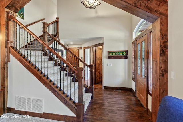 foyer entrance with baseboards, visible vents, stairway, wood finished floors, and a high ceiling