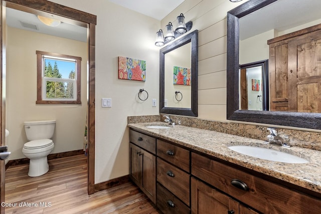 full bathroom with visible vents, a sink, toilet, and wood finished floors