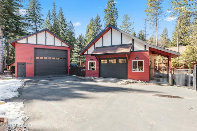 exterior space featuring a gate, fence, a detached garage, and an outbuilding