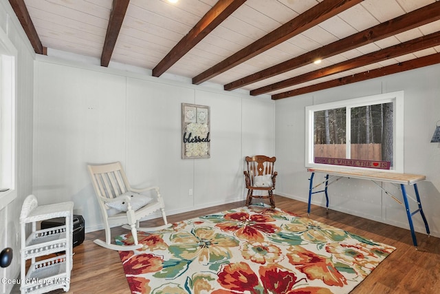 living area with wood ceiling, beam ceiling, baseboards, and wood finished floors