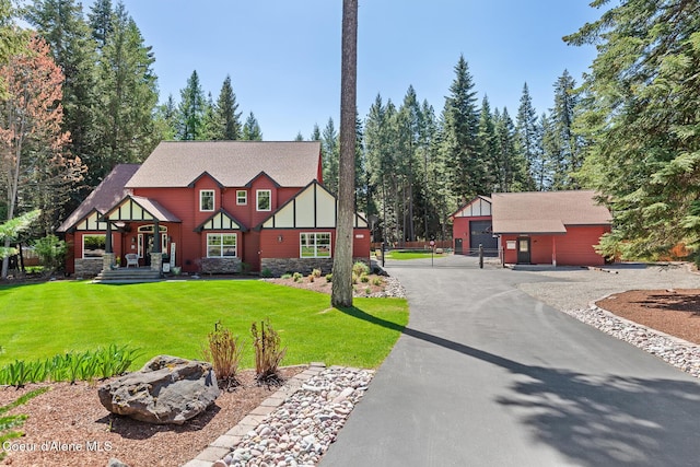12651 N Yearling Cir, Hayden, ID 83835 - tudor-style house with a front yard, a garage, an outdoor structure, board and batten siding, and roof with shingles
