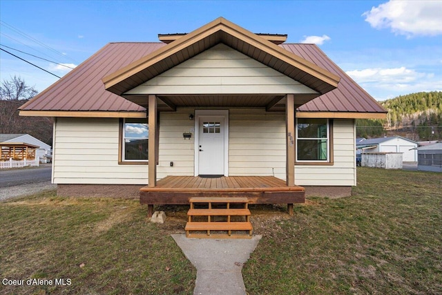 bungalow-style home with a front yard, covered porch, and metal roof