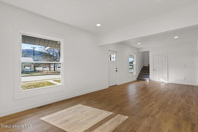 foyer entrance featuring visible vents, plenty of natural light, stairway, and wood finished floors