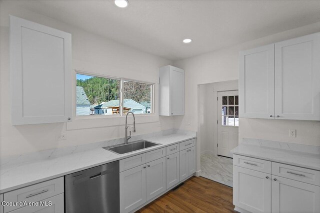 kitchen with light stone counters, white cabinets, dishwasher, and a sink