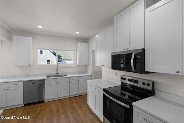 kitchen with white cabinets, stainless steel appliances, a textured ceiling, light wood-style floors, and a sink