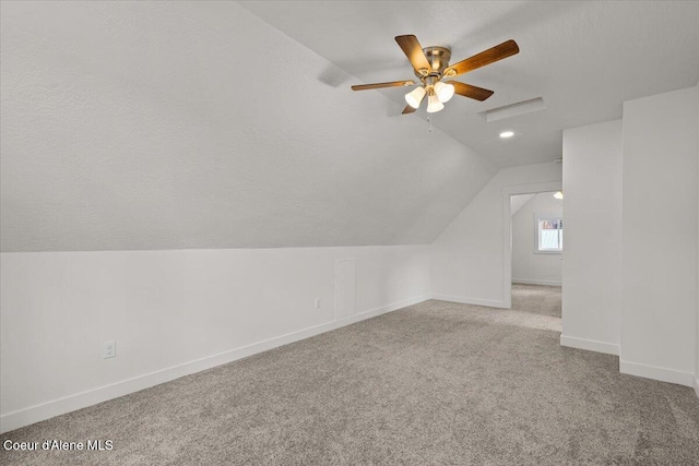 additional living space featuring baseboards, lofted ceiling, ceiling fan, a textured ceiling, and carpet flooring