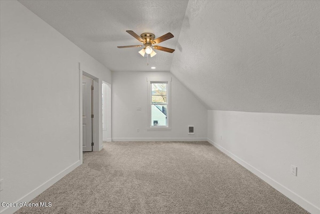 bonus room with light carpet, visible vents, baseboards, vaulted ceiling, and a textured ceiling