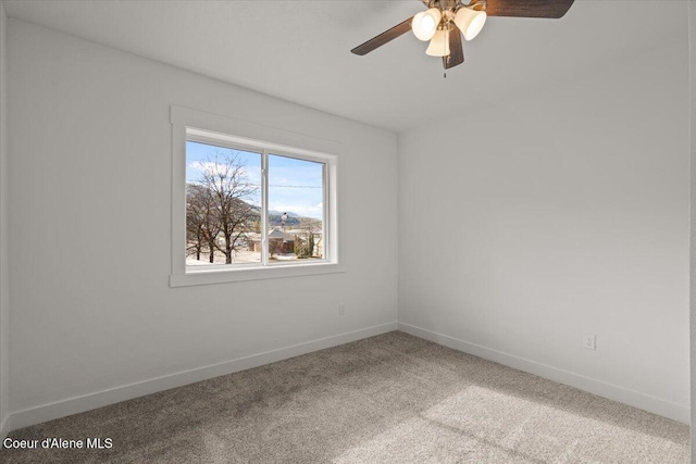 carpeted empty room with baseboards and a ceiling fan