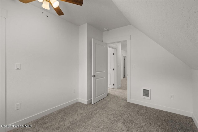 additional living space featuring a textured ceiling, lofted ceiling, visible vents, baseboards, and carpet