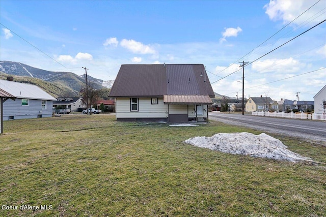 rear view of house featuring a mountain view, metal roof, and a lawn