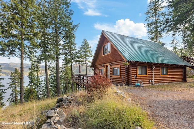 view of side of home with a deck, metal roof, and log exterior