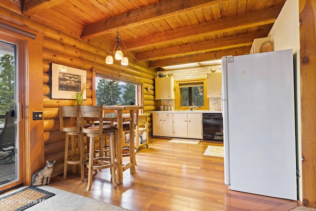 kitchen featuring dishwasher, light countertops, plenty of natural light, and freestanding refrigerator