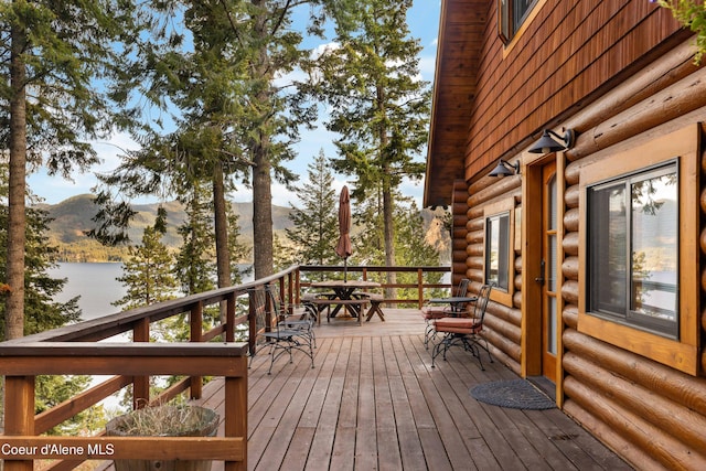 wooden deck with outdoor dining area and a water and mountain view