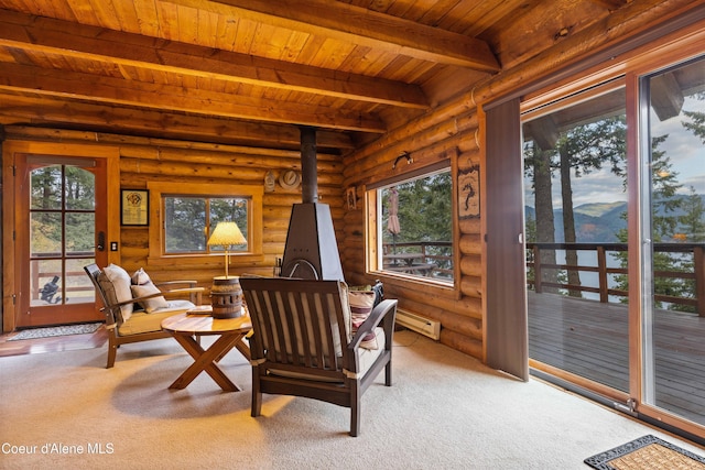 living area featuring wood ceiling, beamed ceiling, a wood stove, carpet, and baseboard heating