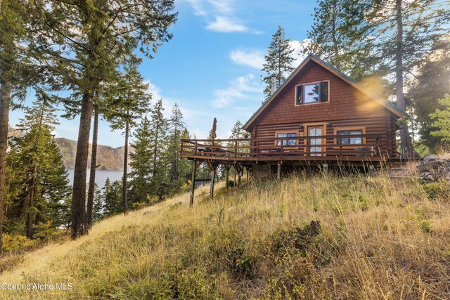 rear view of property with log exterior and a deck with water view