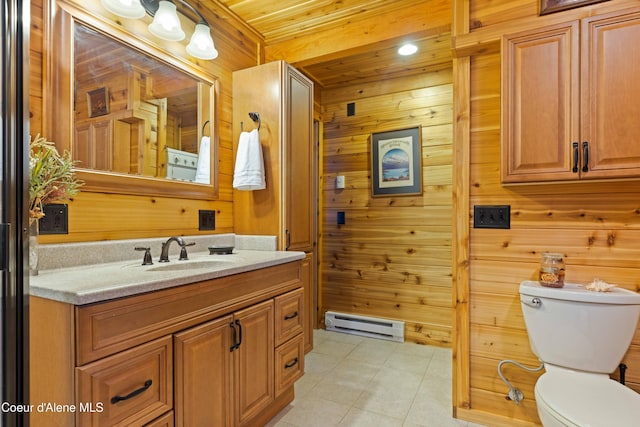 bathroom with toilet, a baseboard heating unit, wood walls, vanity, and tile patterned floors