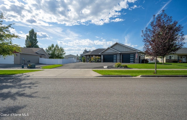 view of front of home featuring fence, driveway, a front lawn, a garage, and board and batten siding