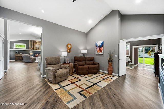 living room featuring baseboards, a lit fireplace, recessed lighting, wood finished floors, and high vaulted ceiling