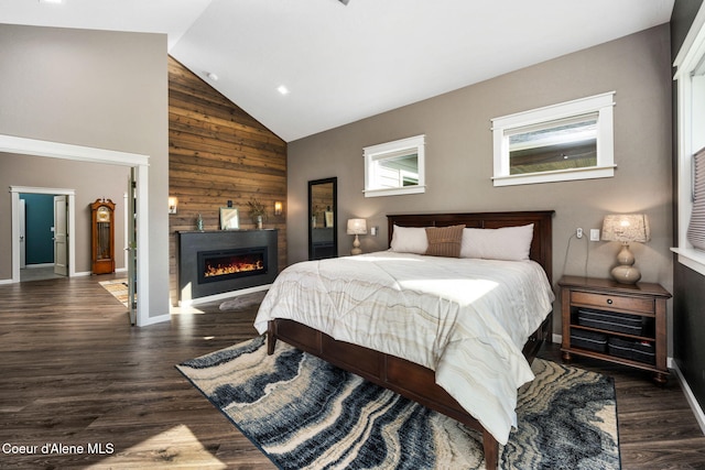 bedroom with baseboards, high vaulted ceiling, a lit fireplace, and wood finished floors