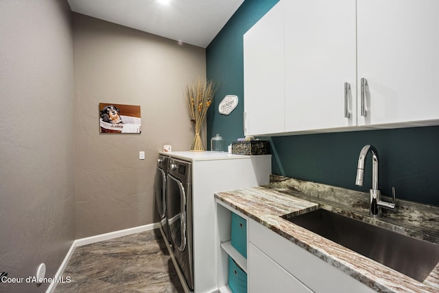 laundry room with baseboards, a textured wall, cabinet space, independent washer and dryer, and a sink