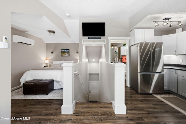 interior space featuring a wall unit AC, dark wood-type flooring, freestanding refrigerator, and a textured ceiling