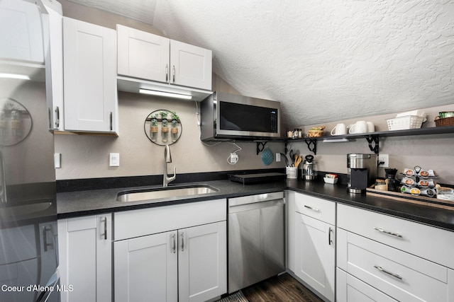 kitchen featuring dark countertops, stainless steel appliances, white cabinets, a textured ceiling, and open shelves