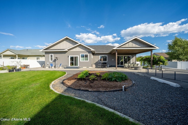 rear view of house featuring a patio, fence, board and batten siding, and a lawn