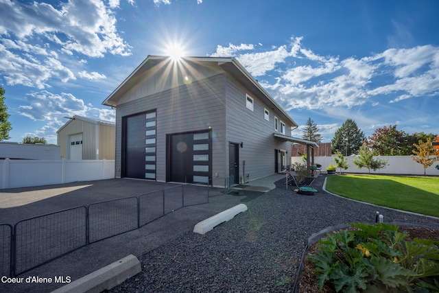 view of side of home with a yard, a garage, board and batten siding, and fence