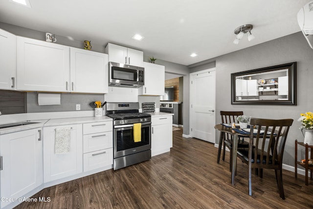 kitchen with dark wood finished floors, a sink, stainless steel appliances, light countertops, and white cabinets