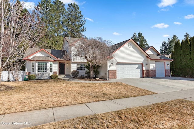 traditional-style home with a garage, brick siding, fence, concrete driveway, and a front lawn