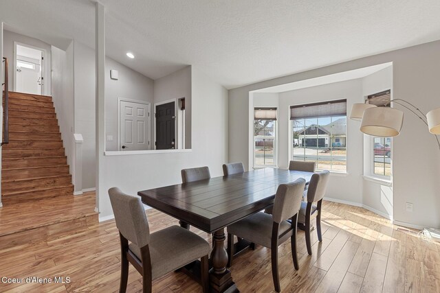 dining space featuring light wood-style flooring, stairway, and baseboards