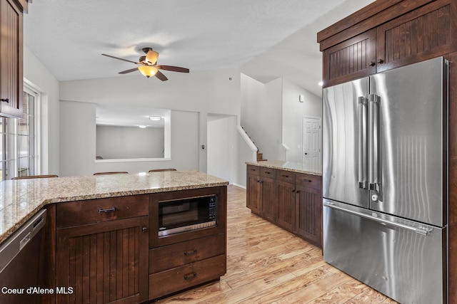 kitchen featuring vaulted ceiling, appliances with stainless steel finishes, light wood-type flooring, and dark brown cabinetry