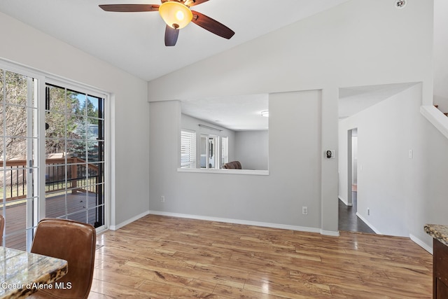 empty room with lofted ceiling, light wood-type flooring, a wealth of natural light, and baseboards