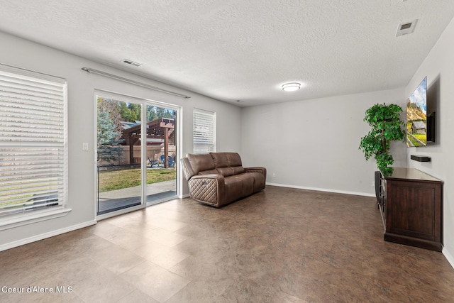 living area with a textured ceiling, visible vents, and baseboards