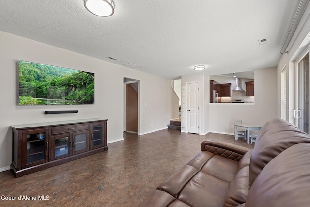 living area with a textured ceiling, visible vents, and baseboards