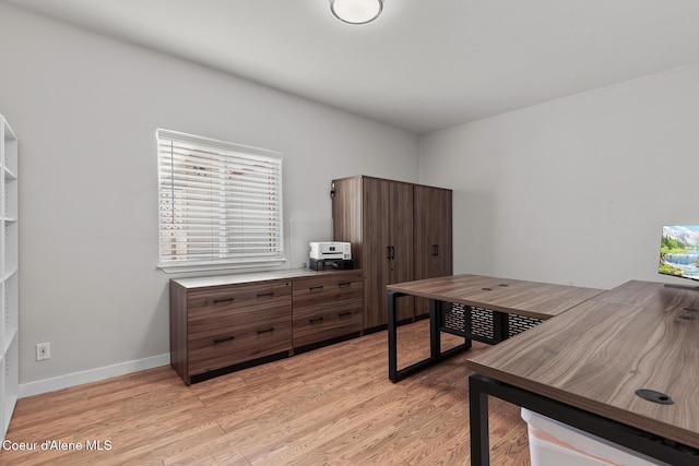 home office with light wood-style flooring and baseboards