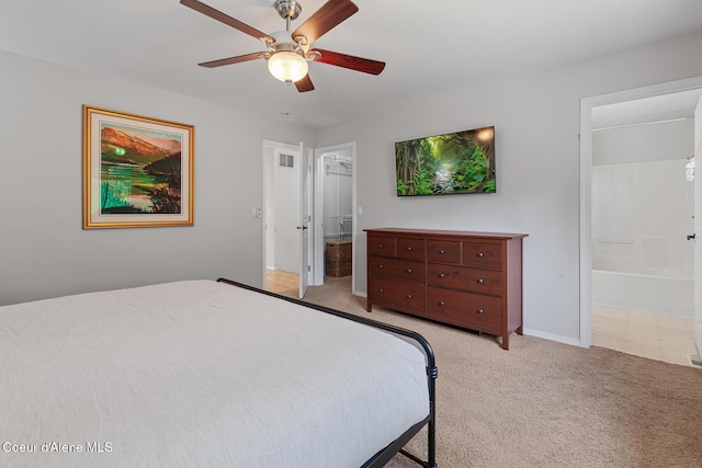 bedroom featuring light carpet, ensuite bath, and a ceiling fan