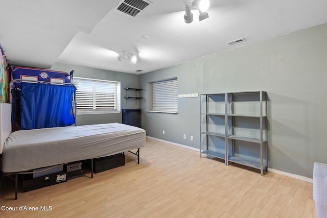 bedroom with wood finished floors, visible vents, and baseboards