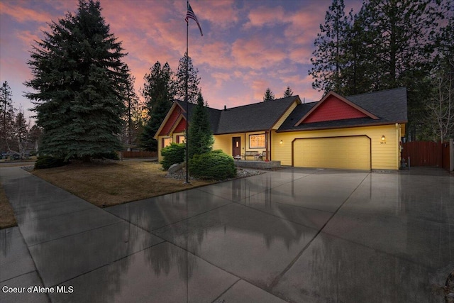 view of front of house with concrete driveway, an attached garage, and fence