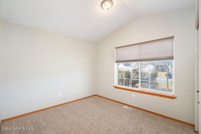 carpeted empty room with visible vents, baseboards, and vaulted ceiling