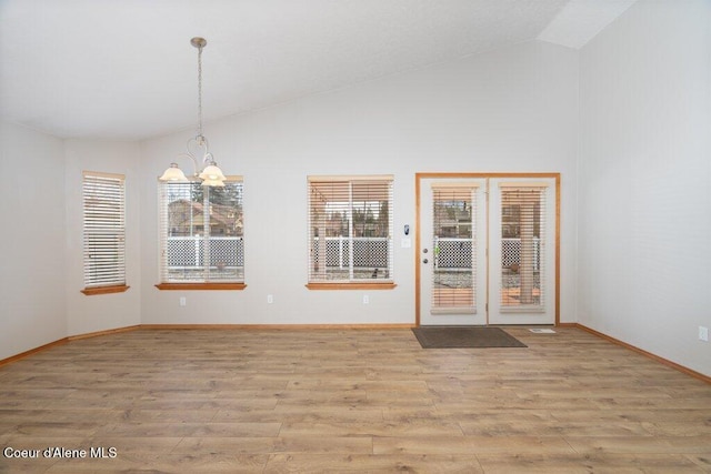 interior space with an inviting chandelier, wood finished floors, a healthy amount of sunlight, and vaulted ceiling