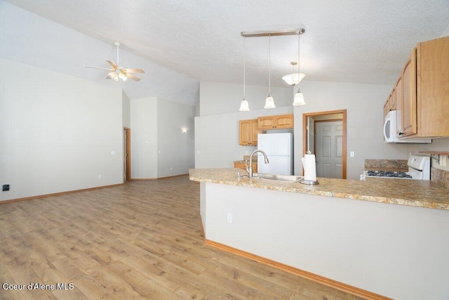 kitchen with light wood finished floors, white appliances, a peninsula, and a sink