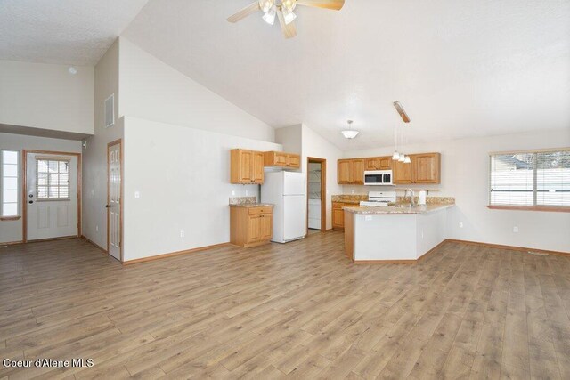 kitchen featuring a wealth of natural light, light wood-type flooring, white appliances, and a peninsula