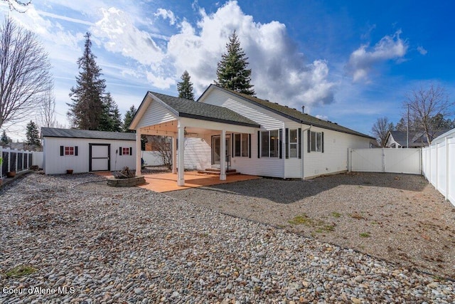 rear view of house with an outbuilding, a fenced backyard, and a gate