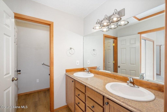 full bath with double vanity, wood finished floors, and a sink