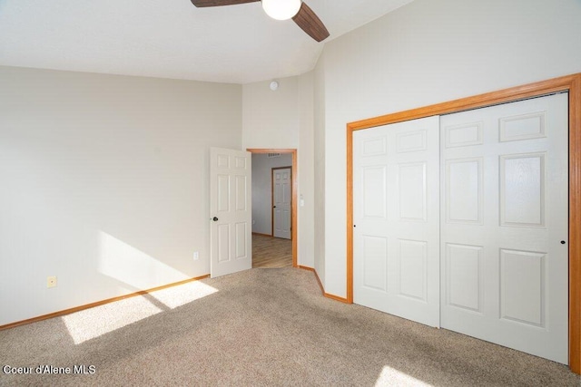 unfurnished bedroom with ceiling fan, baseboards, carpet, lofted ceiling, and a closet